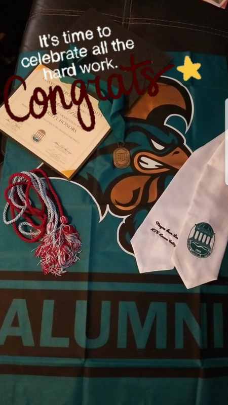 A green gown with a diploma and a tie on it.