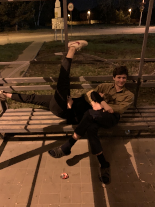 Two people on a bench, one sitting and one lying down.