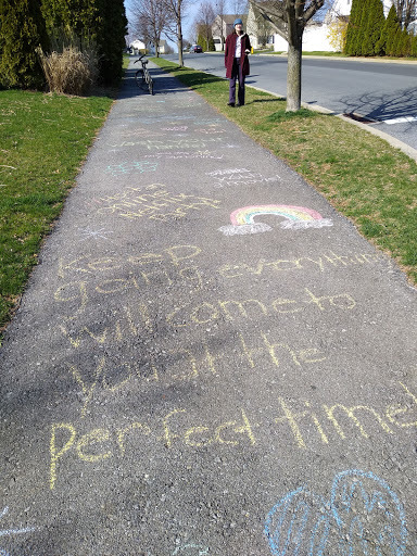 A sidewalk that has uplifting messages written on it in chalk in a neighborhood.