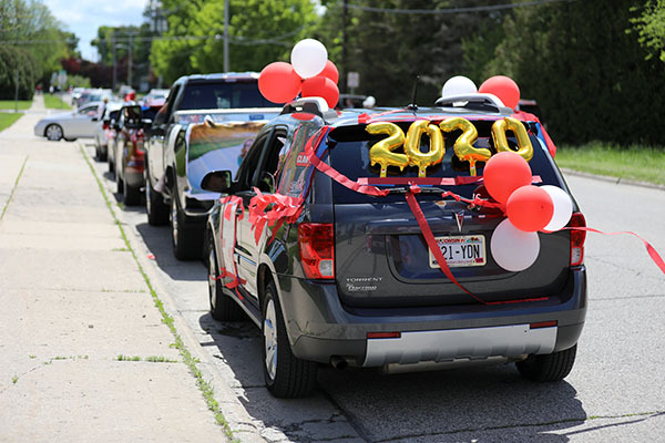 A picture of a line of cars colorfully decorated for high school graduation.  