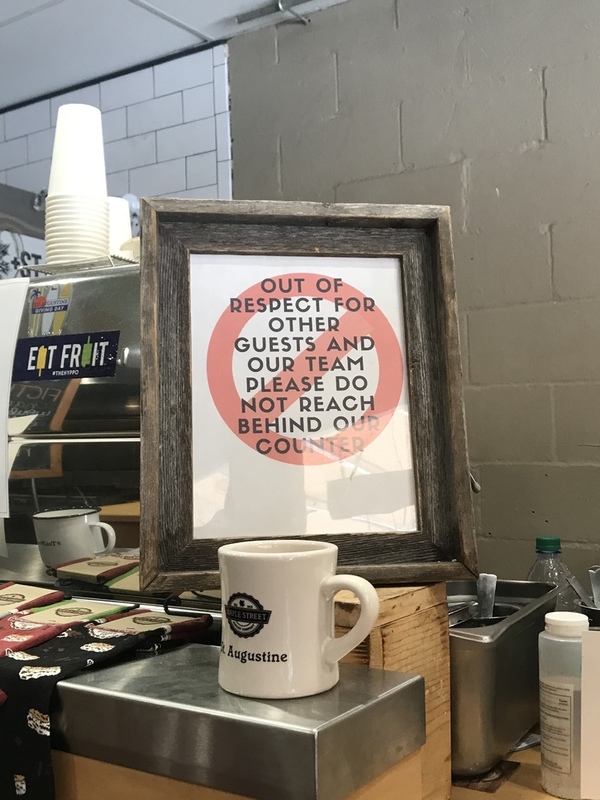 This is a picture of a sign at a restaurant which asked patrons not to reach over the counter and get too close to employees.