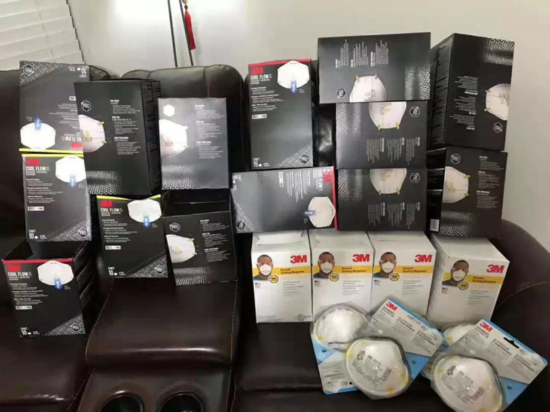 A couch that has numerous boxes of face masks piled on it.