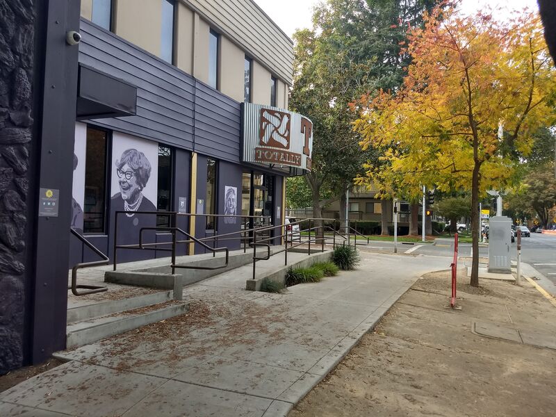 This is a picture taken of a series of murals that are painted on the side of a building. Various women in antiquated clothing are depicted in black and white.