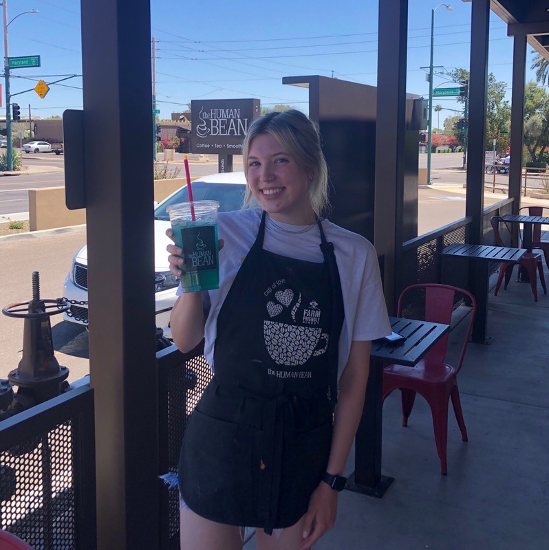 A person with an apron holding a drink. 