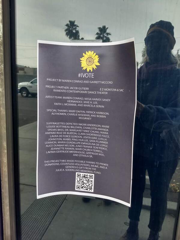 This is a picture of a sign taped to a window of a building. The sign is providing credit for the artists and project managers that helped create a series of murals depicting various suffragettes.