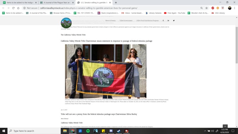 Three people holding up a tribe's flag.