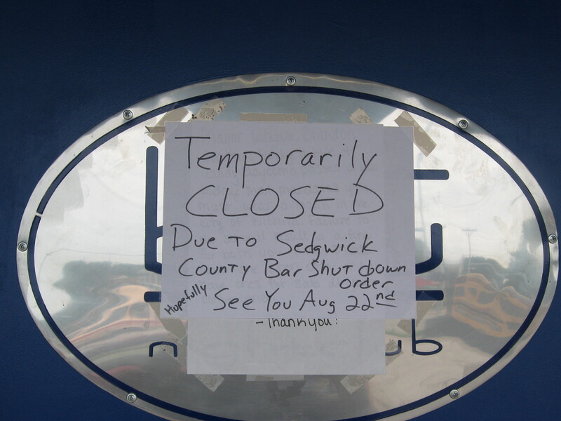 A paper sign reading "Temporarily Closed due to Sedgwick County bar shutdown order. Hopefully see you Aug 22nd".