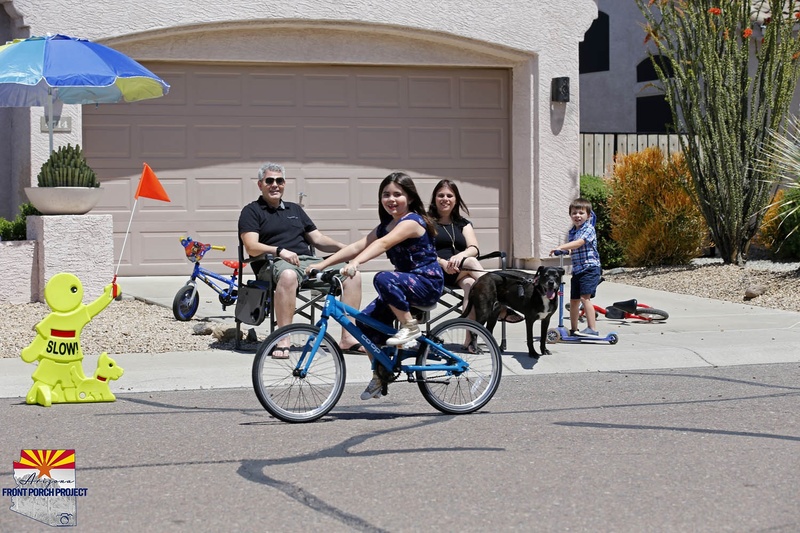 A girl riding a bike in front of a family.