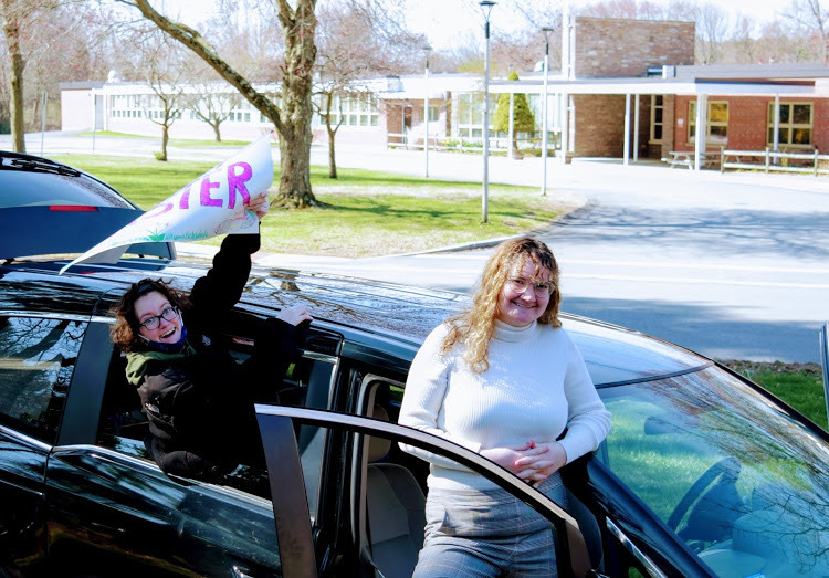 Two women in front of a black vehicle.