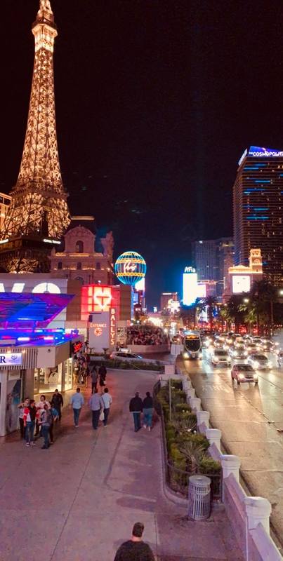 People and cars crowded on a street in front of buildings.