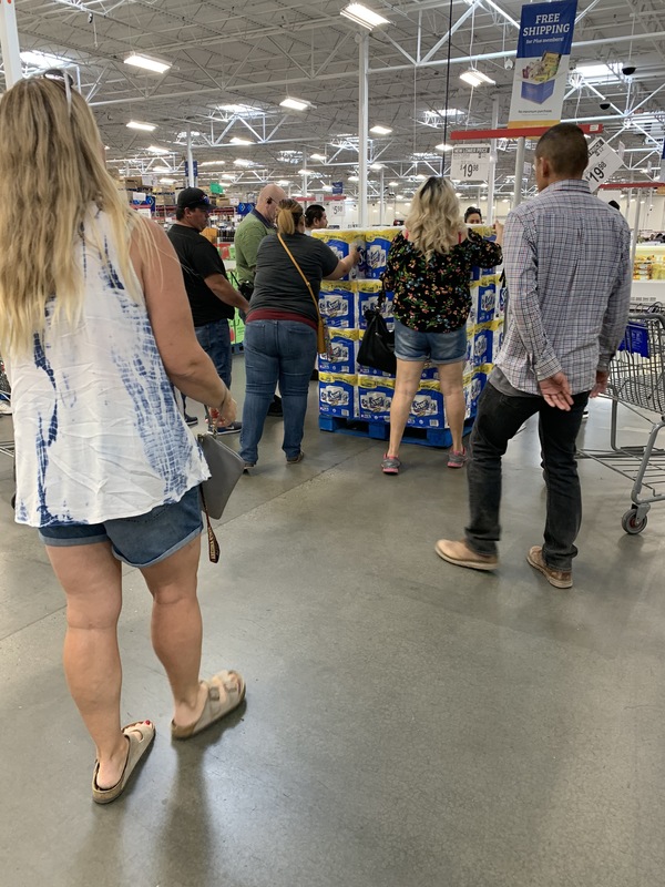 A display of paper towels in a grocery store where people are waiting their turn to grab one.