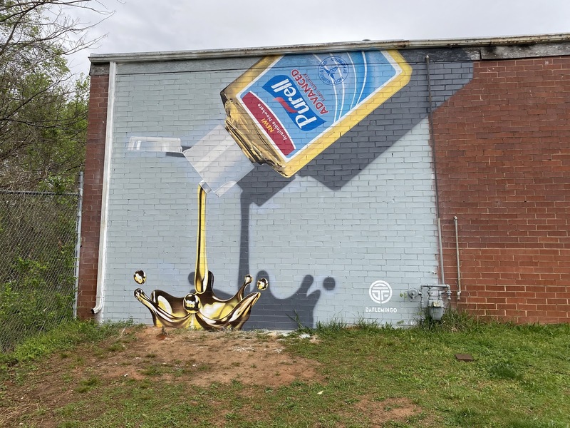 On the side of a building is a mural of Purell hand sanitizer; the sanitizer symbolizes liquid gold.