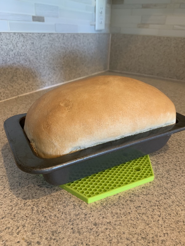 This is a picture of a loaf of freshly baked bread resting on a countertop in a kitchen.