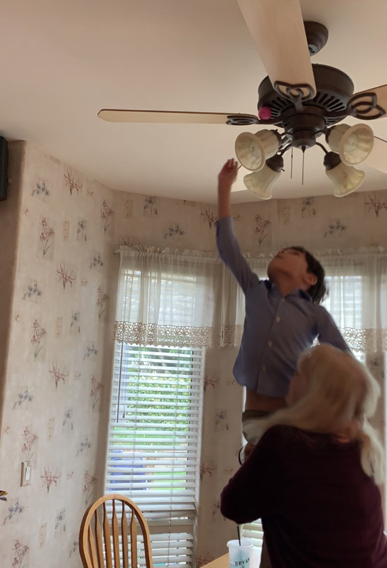 Screenshot of a woman holding a child up to the ceiling.