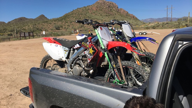 Two dirt bikes are on the back of a pickup truck.