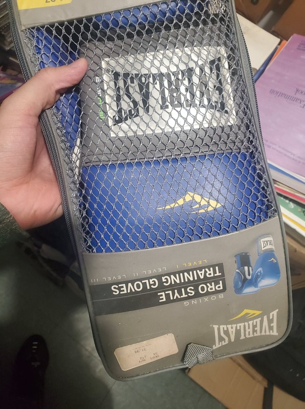 This is a picture of a person holding packaged blue boxing gloves.