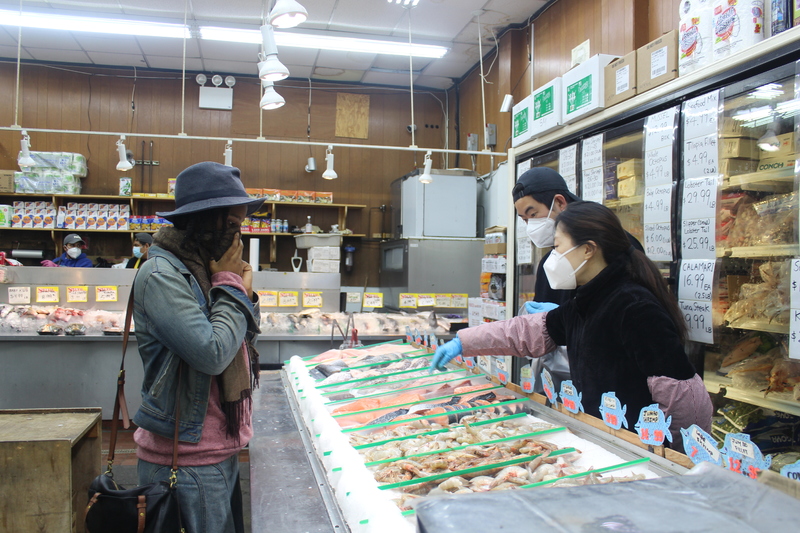 Image of a woman in a mask, shopping for fish.