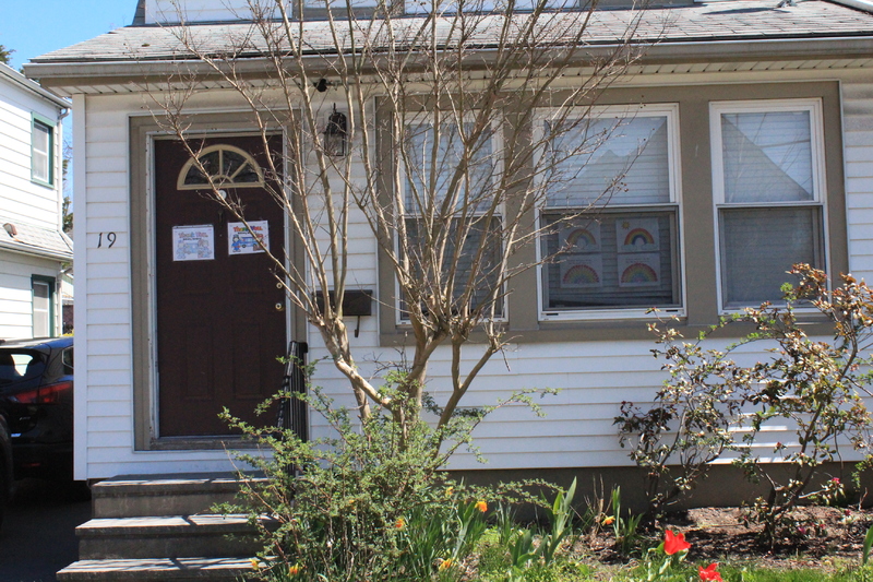 Residential house with a rainbows in the front window and on the front door. 