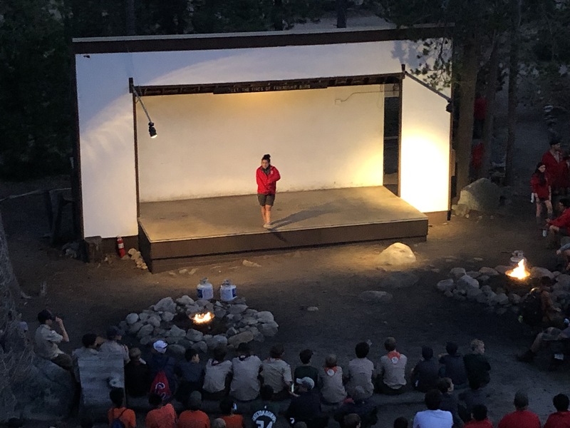 This is a picture of a person on a stage performing for an audience outdoors.