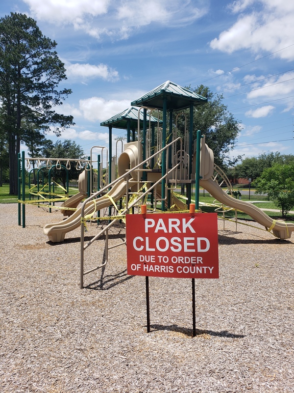 A red sign in front of a playground.