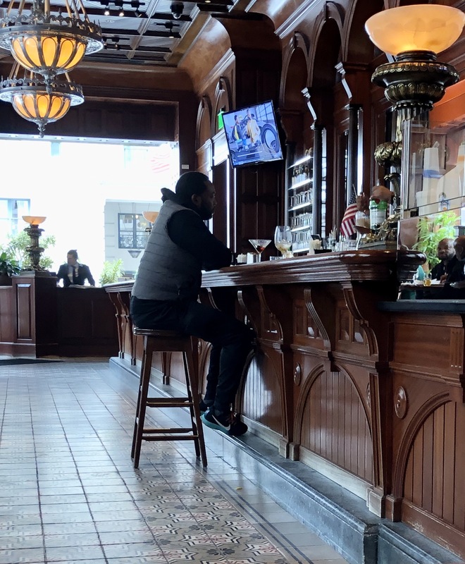 A man sitting at a bar with no other bar stools around him.