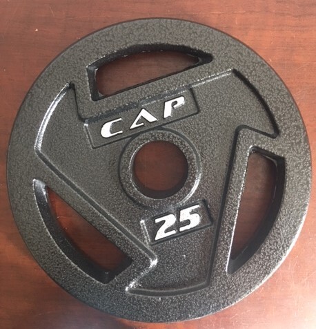 This is a picture taken of a 25 pound exercise weight plate laid down on a wooden floor. 