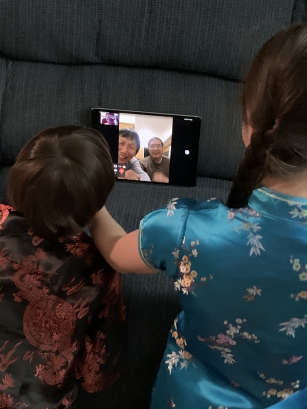 Back of two children FaceTiming with an older couple during Chinese New Year.