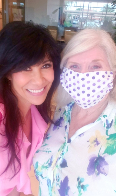 Two people posing for a picture, one with a mask on. 