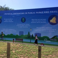 A sign in a park about social distancing.