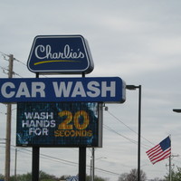 Blue sign for "Charlie's Car Wash" in Wichita, Kansas with white and yellow text saying, " WASH HANDS FOR 20 SECONDS."
