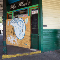 A man waiting for a bus in front of Ms. Mae's Bar in New Orleans.