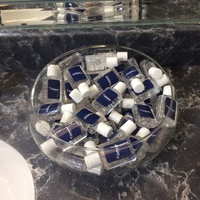 A glass bowl full of travel size hand sanitizer bottles.