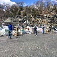 People with masks waiting in line outside of a gated center.