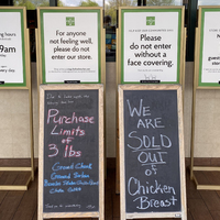 Six signs outside of a Fresh Market detailing COVID-19 protocols as well as sales.