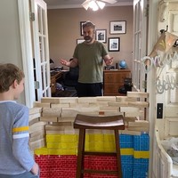 Two people standing next to a makeshift wall in a doorway of a house.
