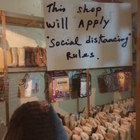 Photo of a sheepskin products shop with a sign on the window that reads, "This shop will apply "social distancing" rules."