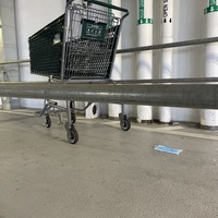 This is a picture of a face mask that has been discarded by a Whole Foods shopping cart in a parking garage.