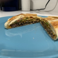 This is a picture taken of a type of grilled quesadilla, with cheese and meat inside.
