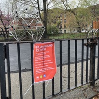 sign tied to a gate stating that a playground is closed due to corona virus