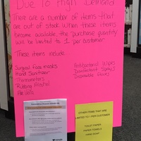 A bright pink sign discussing the high demand of certain products and limiting those products to only 1 per customer. Those products are: surgical face masks, hand sanitizer, thermometers, rubbing alcohol, aloe vera, antibacterial wipes, disinfectant sprays, disposable gloves. On the bottom right is a yellow paper sign attached to the pink sign saying: OTHER ITEMS THAT ARE LIMITED TO 1 PER CUSTOMER TOILET PAPER, PAPER TOWELS, HAND SOAP.