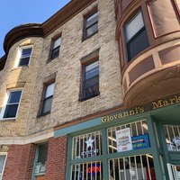 The side of a building has a window open with someone peeking out below their window.