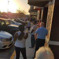 A long line of people are waiting outside of a grocery store.