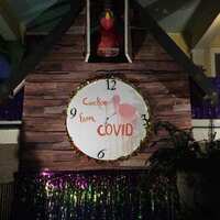 House decorated for Mardi Gras. A white cardboard clock has a pink flamingo in the center and text which reads, "Cuckoo From Covid".